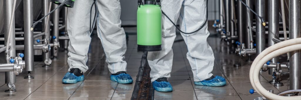 Cleaning of production. Guys in hazmat suits disinfect equipment